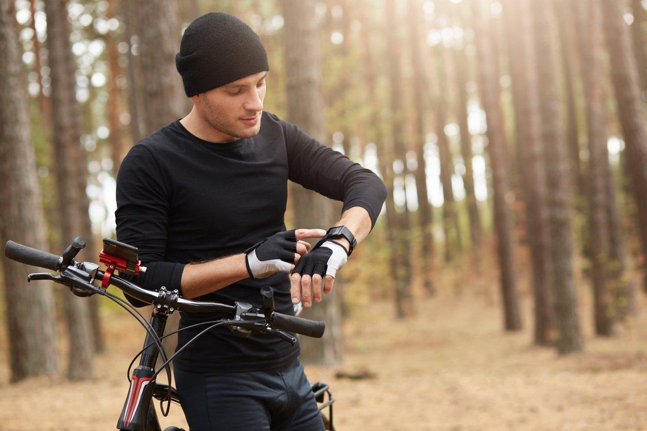 Montre connectée health GPS outdoor utilisée par un cycliste en forêt automnale pour suivre ses performances.