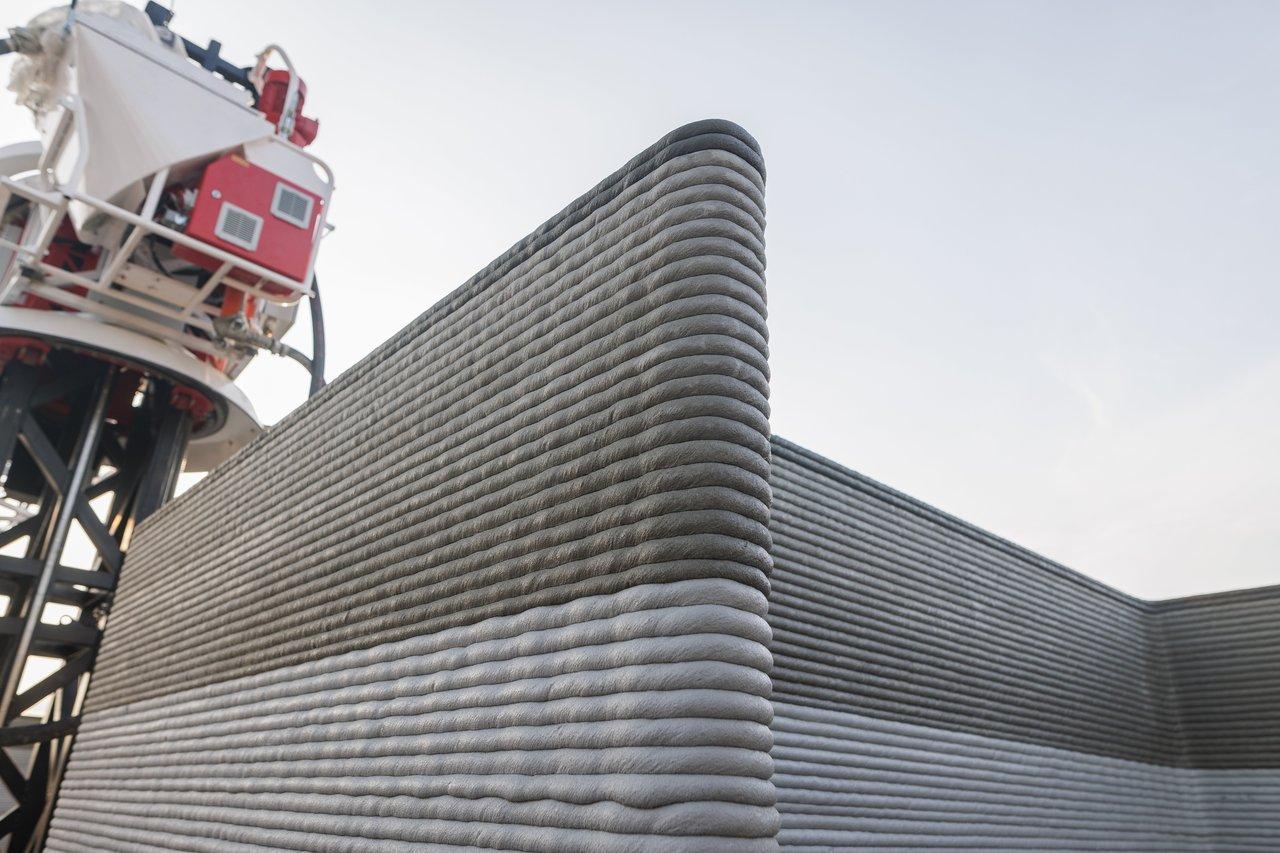 Robot d'impression 3D béton fibré en action sur un chantier moderne, illustrant la révolution de la construction avec la technologie.
