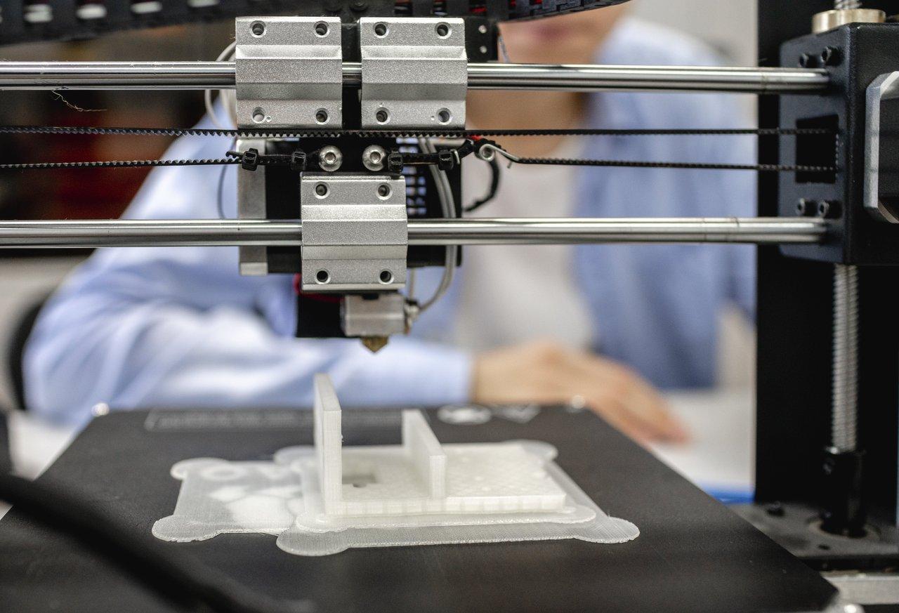 Technicien surveillant une impression 3D dans un laboratoire médical dédié à la fabrication additive en santé.